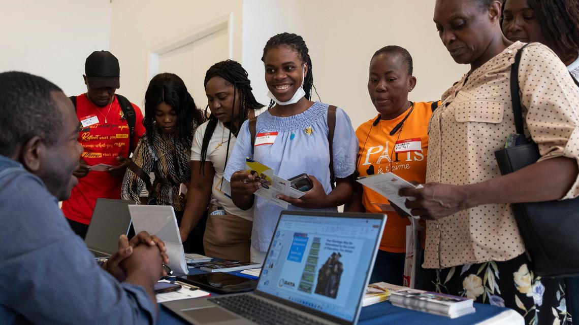 Wanita Fidele, 18, center, talks with Junior Pierre, with the Sant La Haitian Neighborhood Center, during a community resource fair at the Magic City Innovation District in Little Haiti. The fair aimed to help recently arrived Haitians and other immigrants connect with health care providers, legal services and prospective employers.