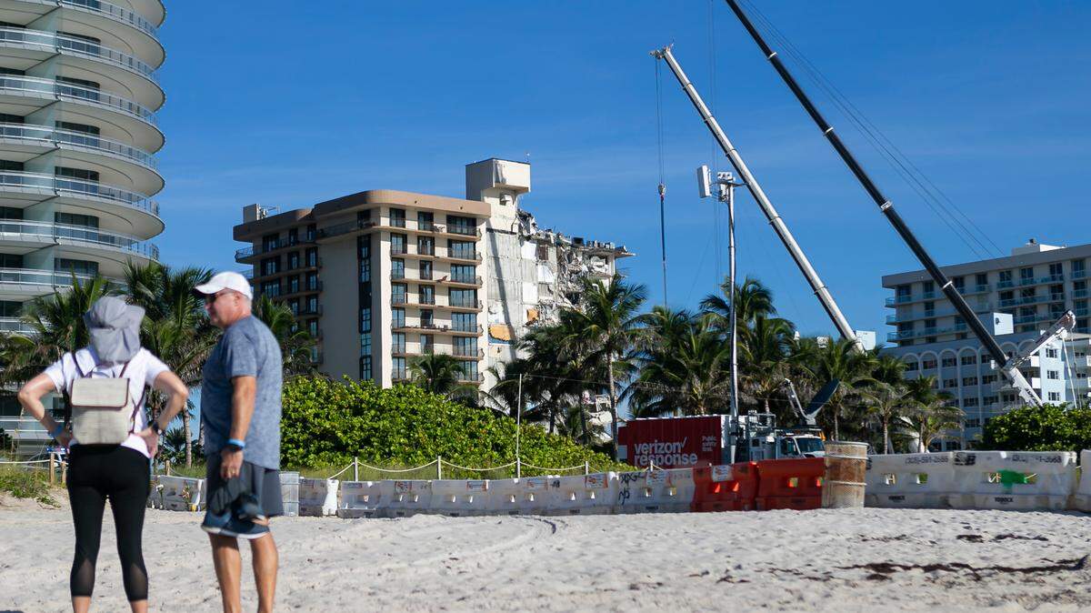 Beachgoers watch nearby as rescue teams continue to looks through rubble for survivors at the partially collapsed Champlain Towers South Condo building in Surfside, Florida on Saturday, July 3, 2021.