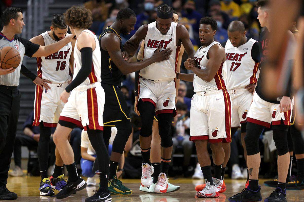 SAN FRANCISCO, CALIFORNIA - JANUARY 03: Jimmy Butler #22 of the Miami Heat is helped up by Kyle Lowry #7 of the Miami Heat and Draymond Green #23 of the Golden State Warriors after he slipped and injured himself in the second half at Chase Center on January 03, 2022 in San Francisco, California. NOTE TO USER: User expressly acknowledges and agrees that, by downloading and/or using this photograph, User is consenting to the terms and conditions of the Getty Images License Agreement. (Photo by Ezra Shaw/Getty Images)