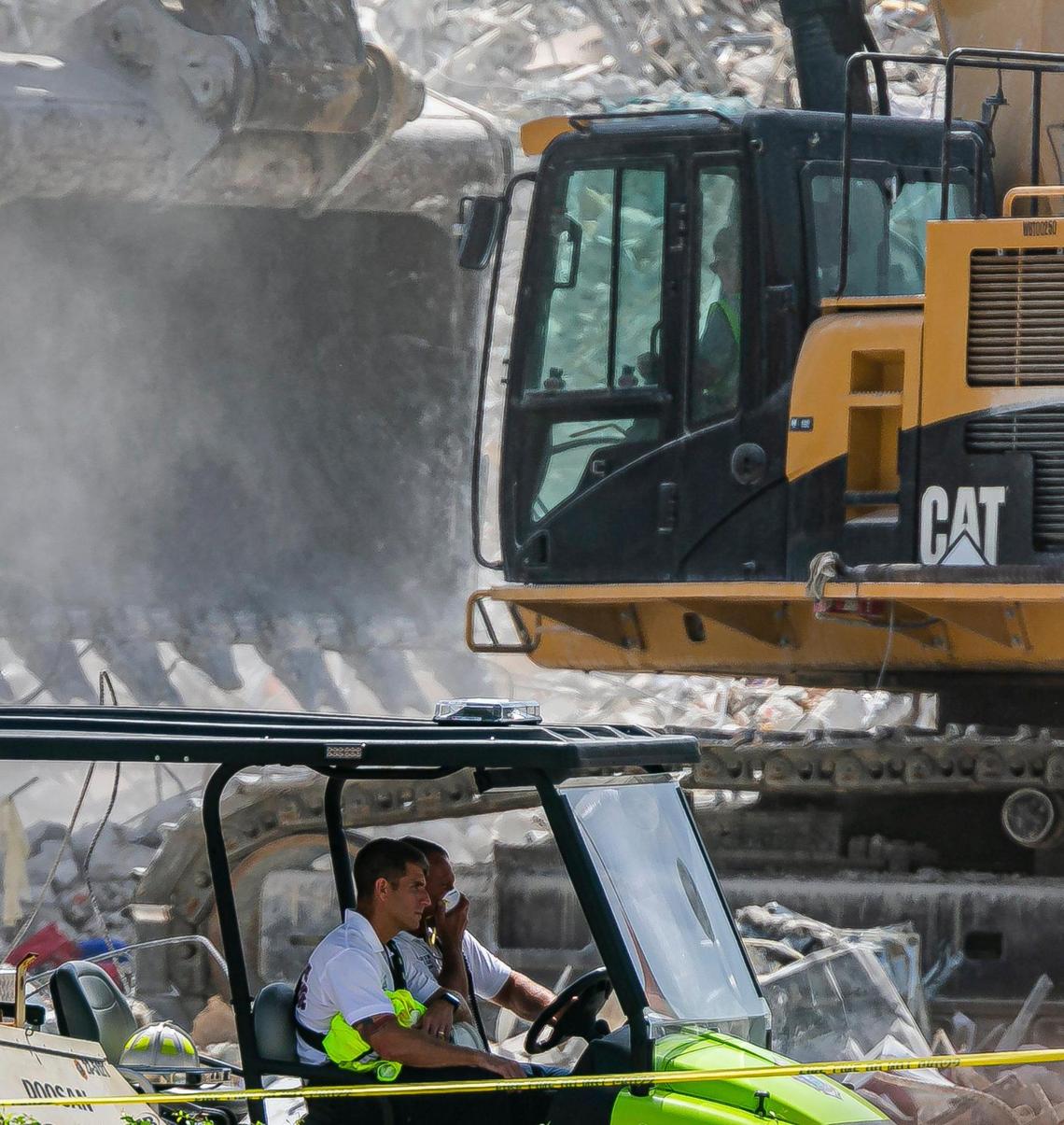 Rescue workers drive by the pile of debris and rubble that remains of the collapsed Champlain Towers South condo in Surfside, Florida on Friday, July 9, 2021.