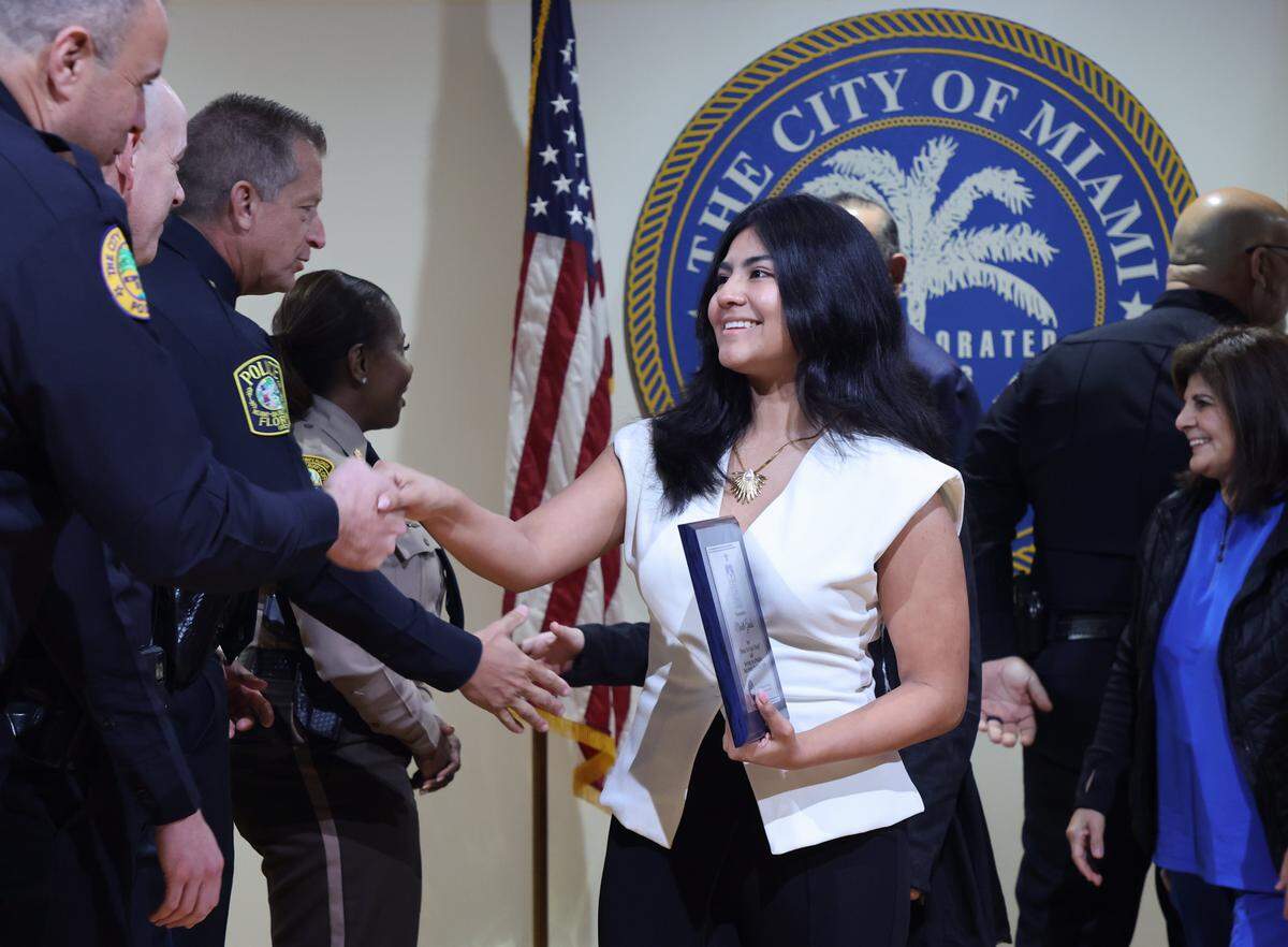 Student Michelle Grados, center, shakes the hands of law enforcement officers as she and family go on stage to receive her award.   The Do The Right Thing Program and Miami Police honored nine outstanding students out of over 700 nominees for their courage, compassion, and leadership inside the auditorium of the Chief Clarence Dickson Police College on Wednesday, January 21, 2026, in Miami, Florida. 