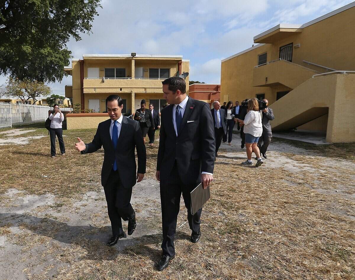 Then-HUD Secretary Julian Castro, left, and Comcast executive Derek Cooper walk through the Rainbow Village public housing complex in 2016.