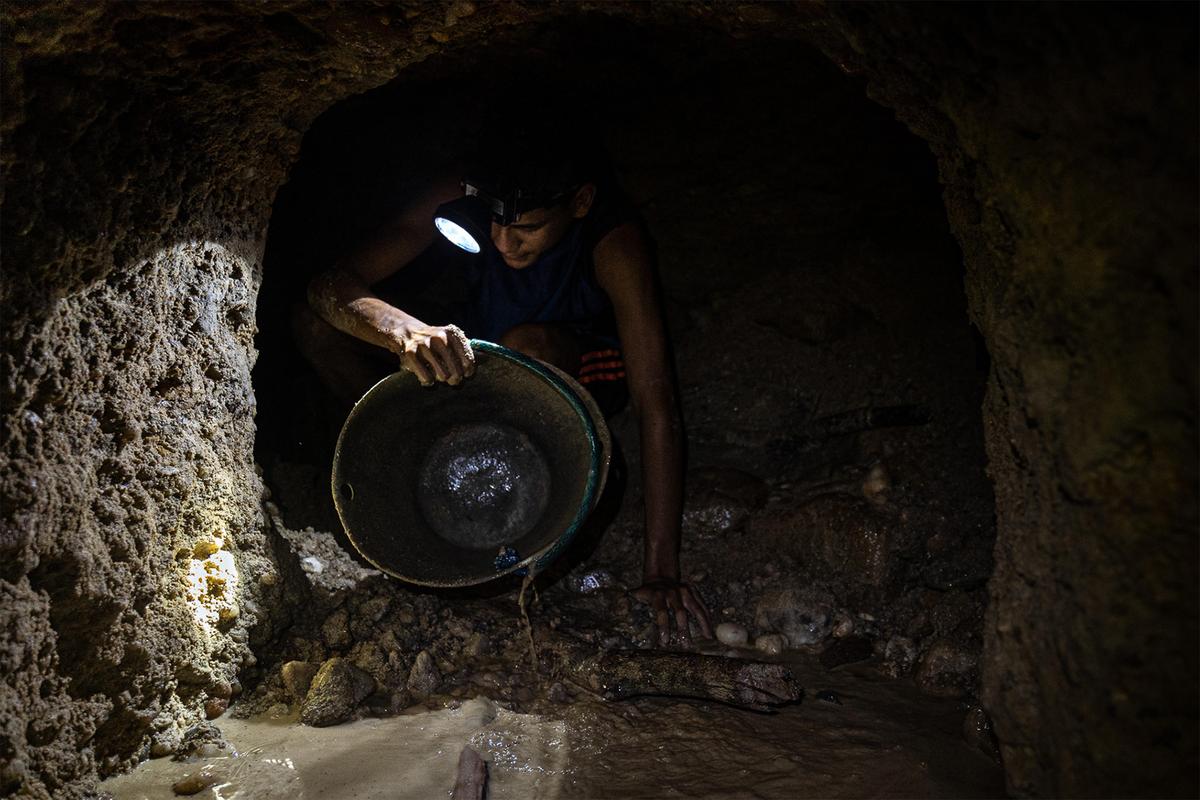 Un minero saca agua con un cubo en la mina Las Parcelas, Tumeremo. Algunas veces, especialmente durante la temporada de lluvias, las minas se inundan y las paredes colapsan, provocando la muerte de trabajadores. "Lo que la mina te da, la mina te lo quita", dicen los mineros.