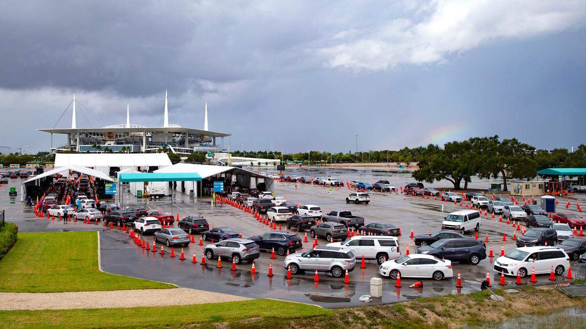 Vehicles line up as health care workers help to check in people being tested at the COVID-19 drive-thru testing center at Hard Rock Stadium in Miami Gardens, Florida on Sunday, Nov. 22, 2020.