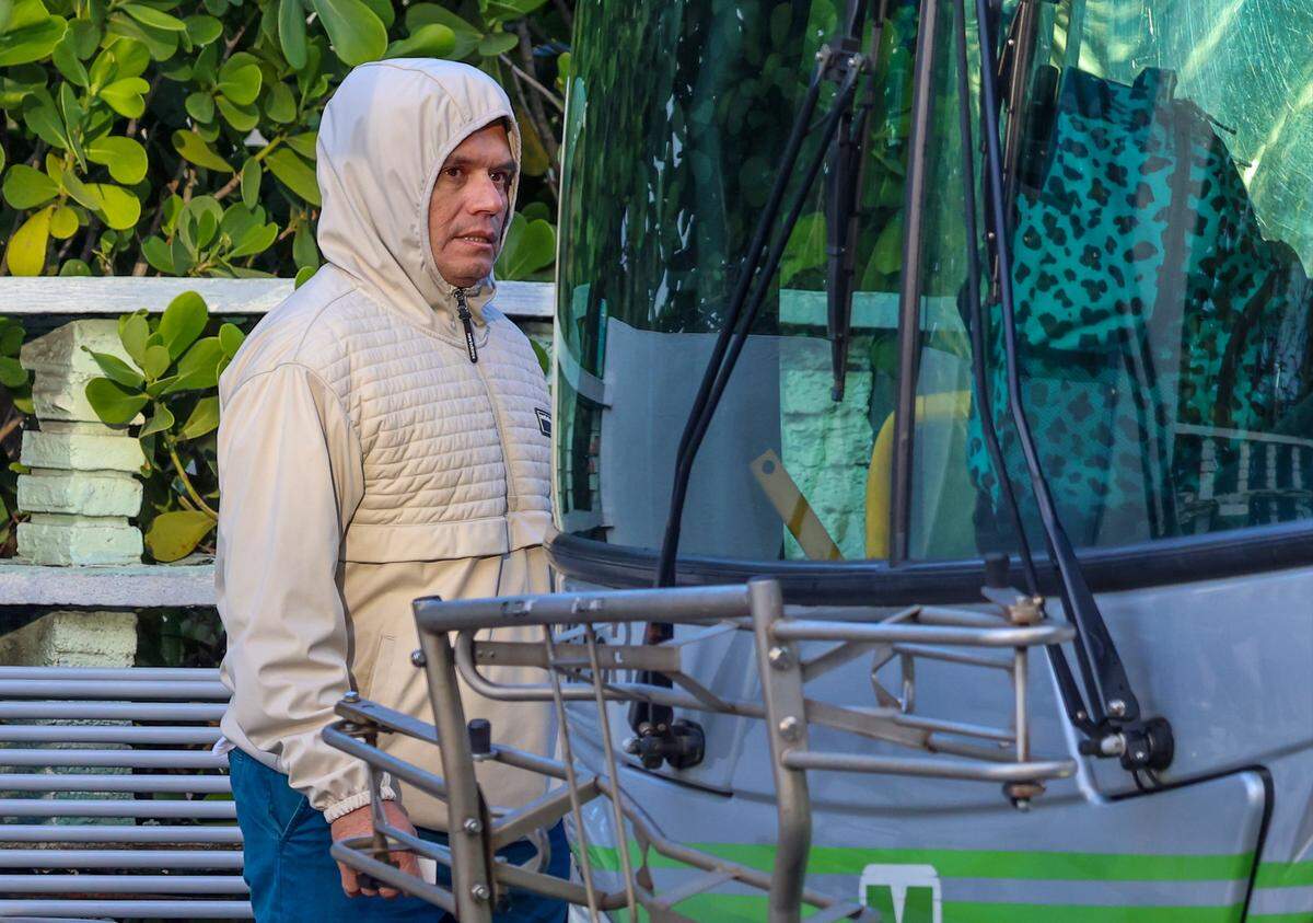 Hoodies, sweaters, coats, gloves, and knit hats are the attire for cool morning air as temperatures dropped due to arctic air on Tuesday, Nov. 11, 2025, in Miami, Florida. A public transit commuter boards a bus dressed for the weather.