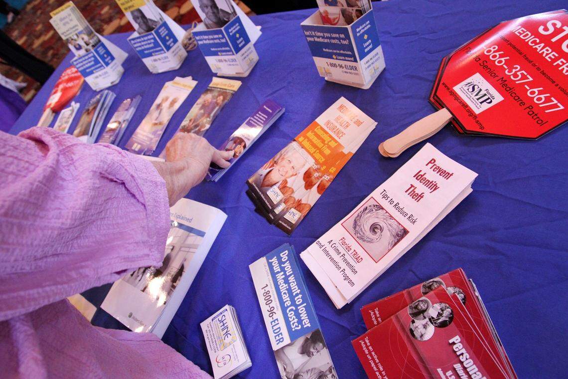 Carol Fisher picks up information on Medicare at the SHINE, Serving Health Insurance Needs of Elders, table at a senior health fair.
