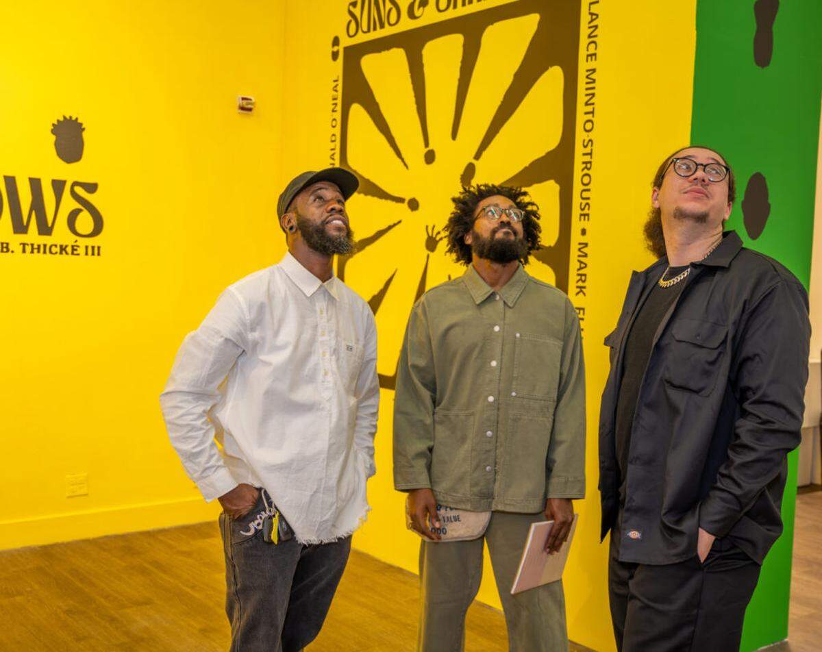 From left, Roscoè B. Thické III, Mark Delmont, and Lance Minto-Strouse survey the exhibition.