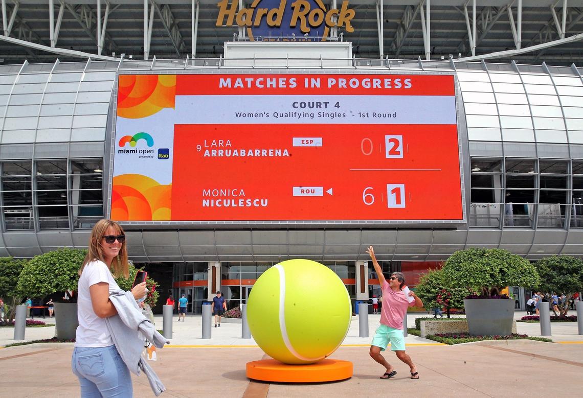 Agustina and Alfredo Robledo have fun with the tennis ball sculpture outside Hard Rock Stadium at the 2019 Miami Open in Miami Gardens, Florida, Monday, March, 18, 2019.