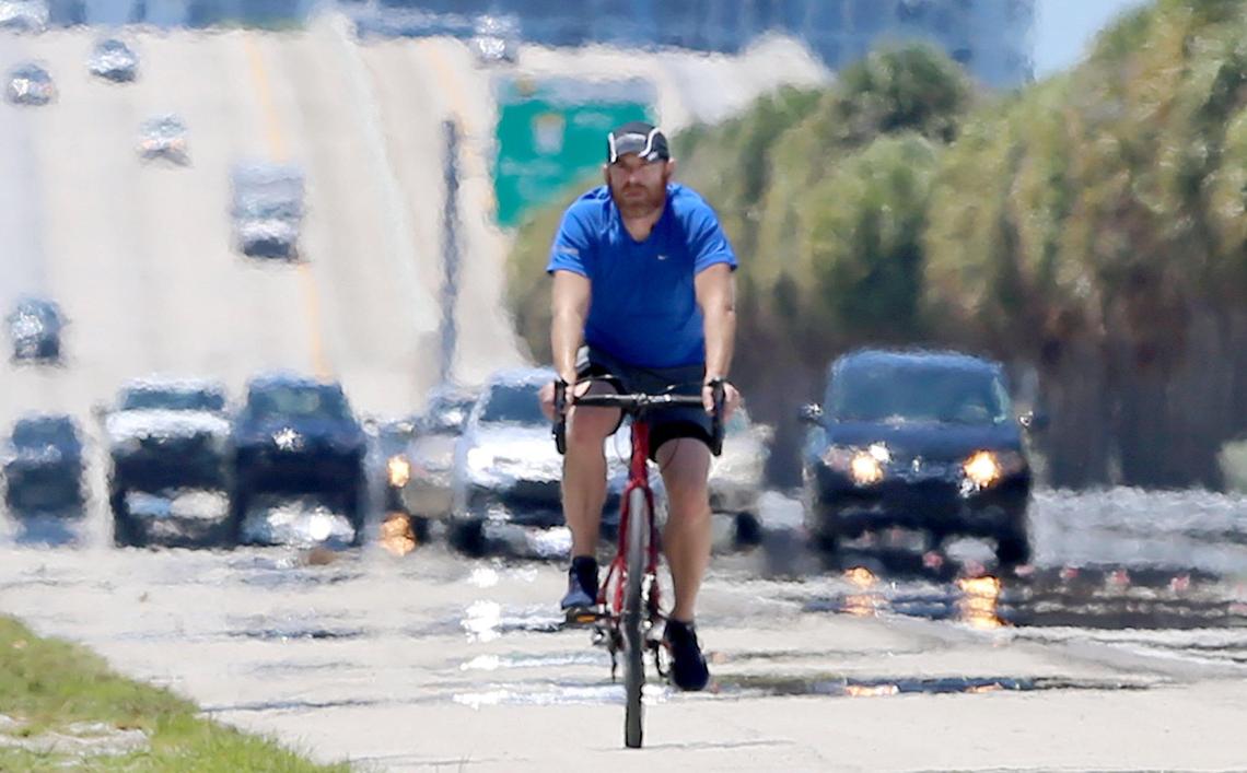 A biker rides alongside cars on the eastbound Julia Tuttle Causeway. Traffic congestion is down, rush hour has evaporated due to the coronavirus pandemic, and speeding, especially excessive, dangerous speeding, is way up on empty roads.