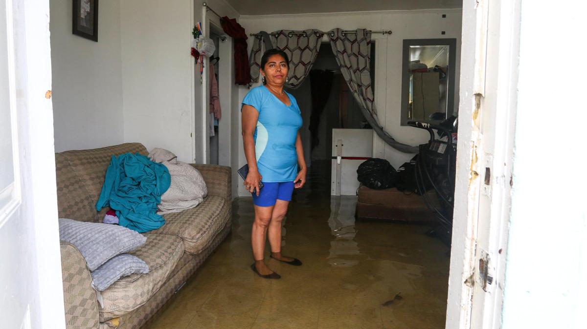 Alba Nubia Flores, who lives on Southwest Third Street, stands in the living room of her flooded rental home in the neighborhood of Little Havana in Miami, Florida, on Saturday, June 4, 2022.