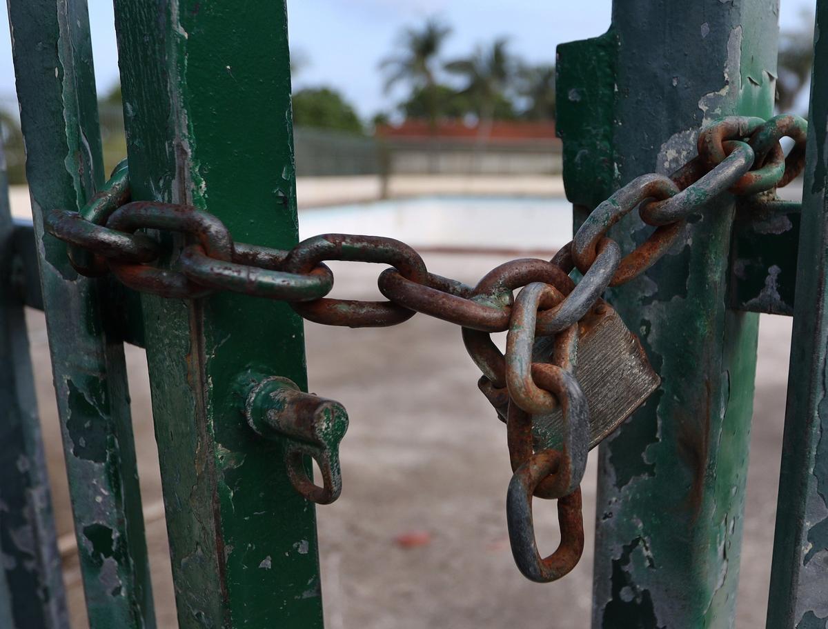 A rusted lock and chain dangle from the gate of the fence that surrounds the closed Morningside pool for the fourth straight summer.
