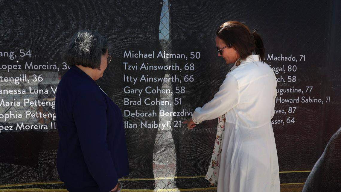 Ronit Naibryf, right, points out her son’s name to Miami-Dade County Mayor Daniella Levine Cava at the temporary memorial site at the Champlain Towers South condo site in Surfside on May 12.