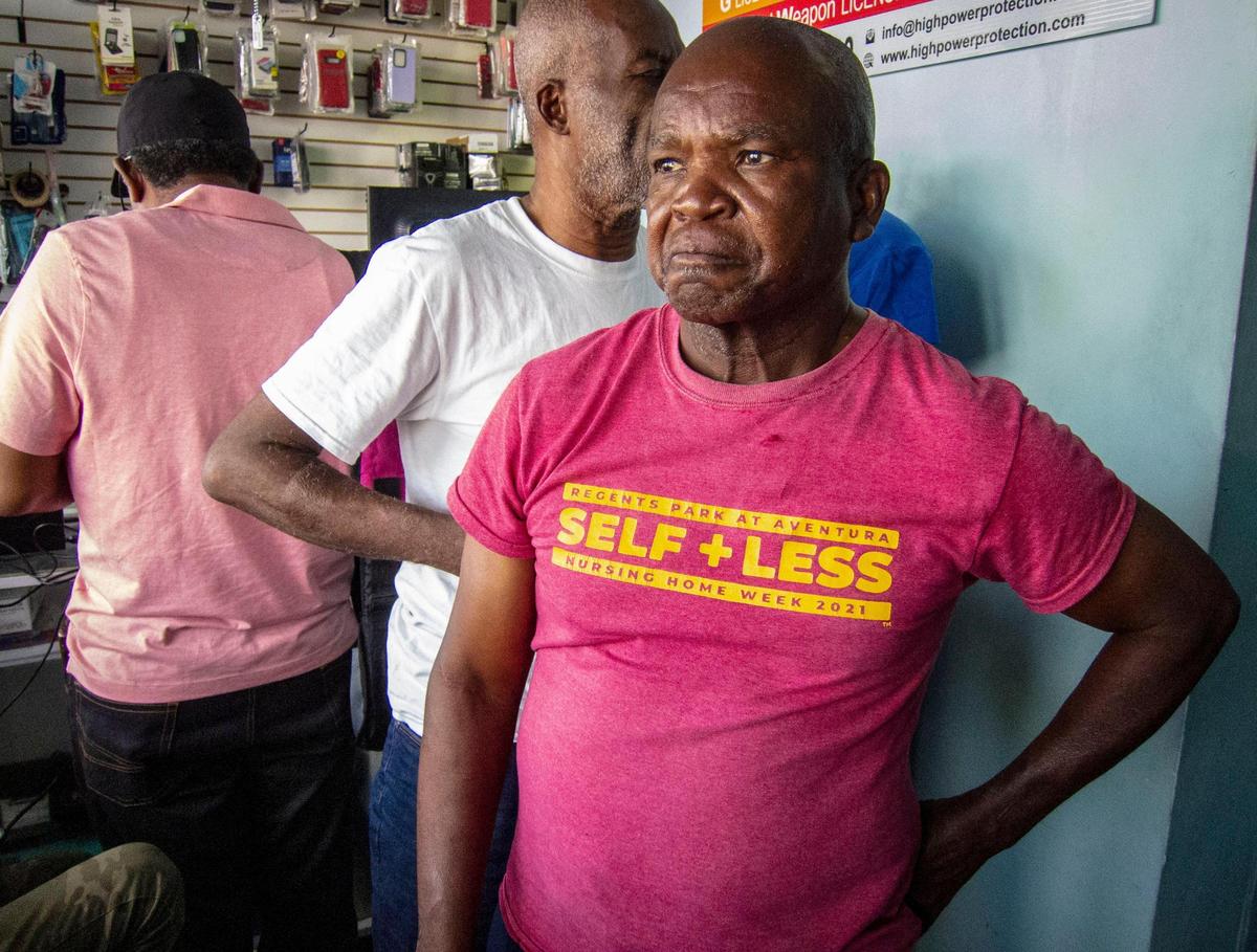 Eliantes Jean Jacques, right, who lost two family members to gang violence in Port-au-Prince pauses after discussing details of his painful loss with a Miami Herald reporter inside Clariteck, a store in North Miami.
