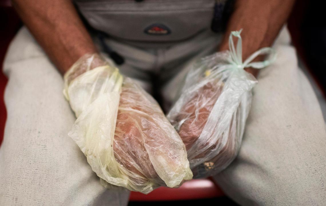 A man wearing plastic bags as gloves as a precaution amid the spread of the new coronavirus rides the subway in Caracas, Venezuela, Monday, March 30, 2020.
