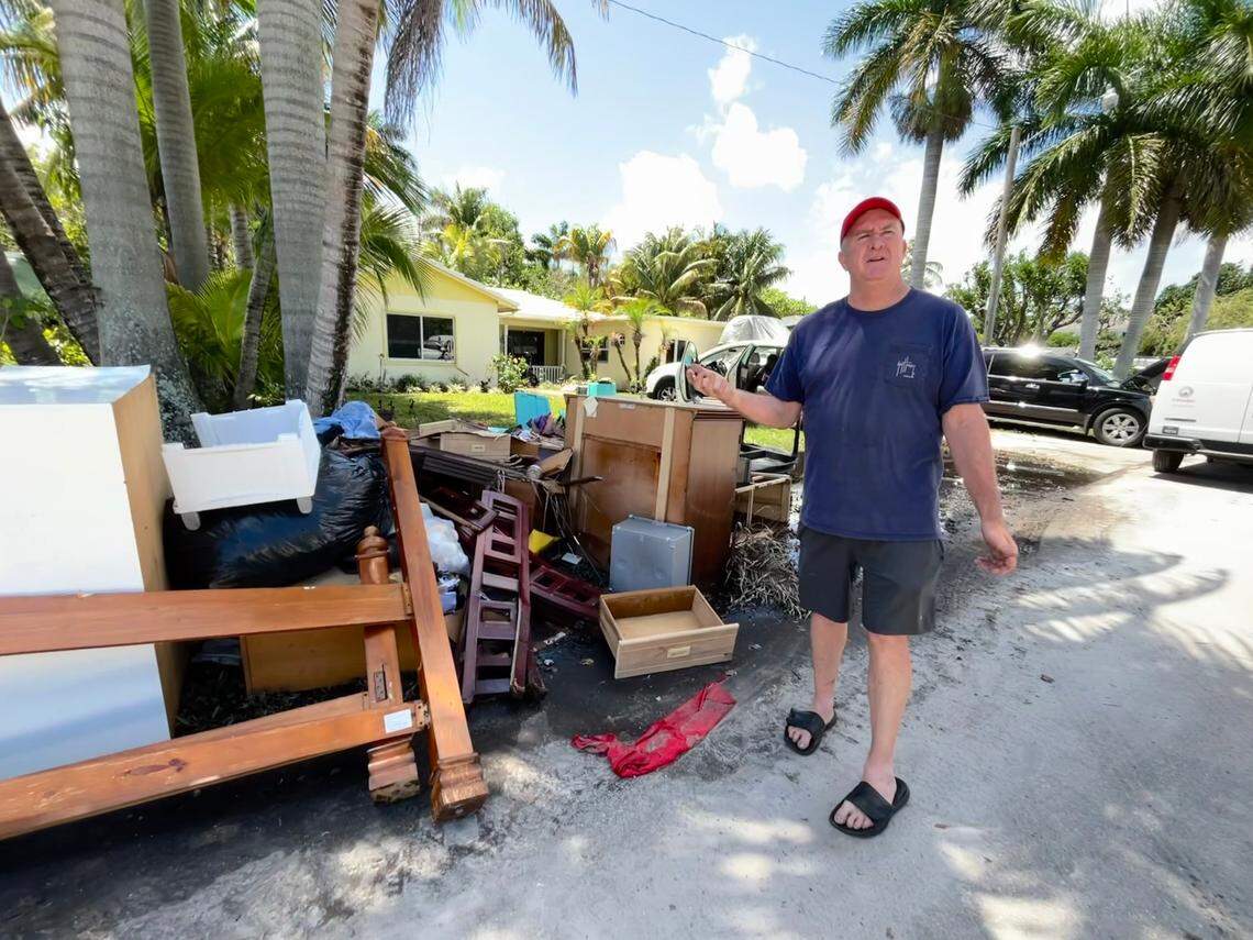 Lance Peterson, 56, stands in front of his waterlogged belongings and ruined vehicles after his Fort Lauderdale home saw three feet of flooding. He found his elderly mother floating on a mattress in the living room Wednesday evening.