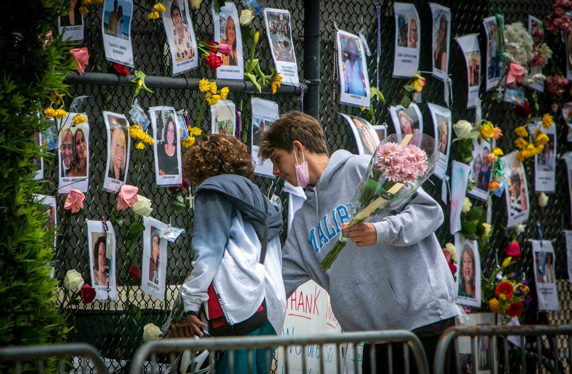 Two boys place flowers on a makeshift memorial near the site of the collapsed condominium on June 28, 2021.