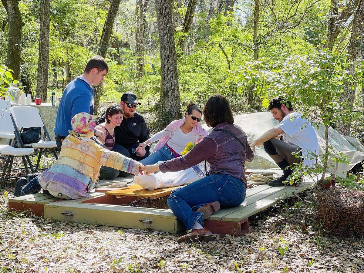 Mourners join hands before a body is lowered into a grave at Prairie Creek Conservation Cemetery near Gainesville, Florida.