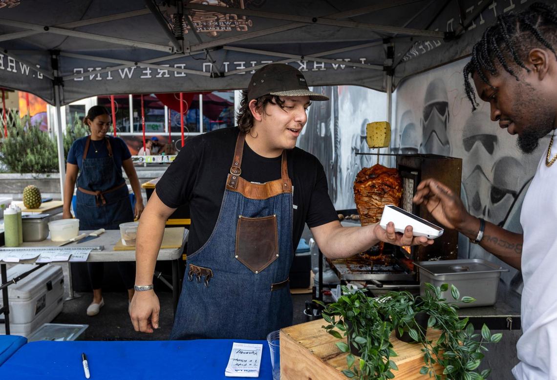 Eduardo Lara, center, takes payment from a customer in front of J. Wakefield Brewing in Wynwood, where he sells his “callejero” street tacos.