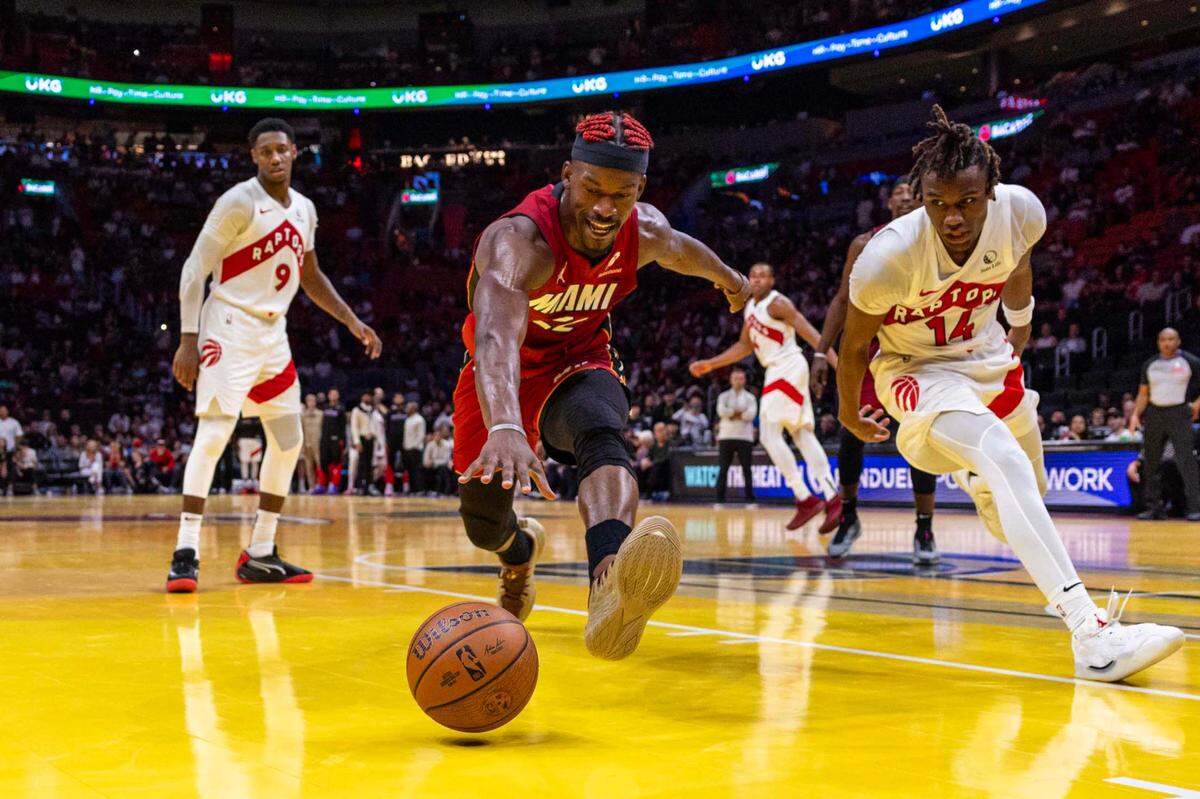 Miami Heat forward Jimmy Butler (22) chases a loose ball while guarded by Toronto Raptors guard Ja’Kobe Walter (14) during the second half of an NBA game at Kaseya Center on Friday, Nov. 29, 2024, in Miami, Fla