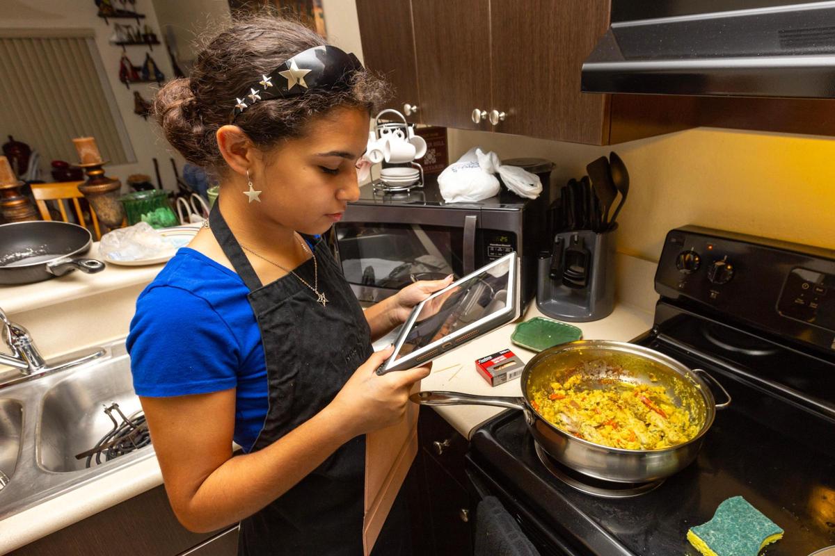 Adrienne Rosquete, 15, photographs her finished One Pot Coconut Curried Chicken with peas, caramelized onions and peepers during a cookingclass hosted by FIU School of Hospitality on how to cook healthy meals in real time, from her home at Verde Gardens, a 145-unit townhome community for formerly homeless residents, in Homestead, Florida, on Tuesday, October 24, 2023.