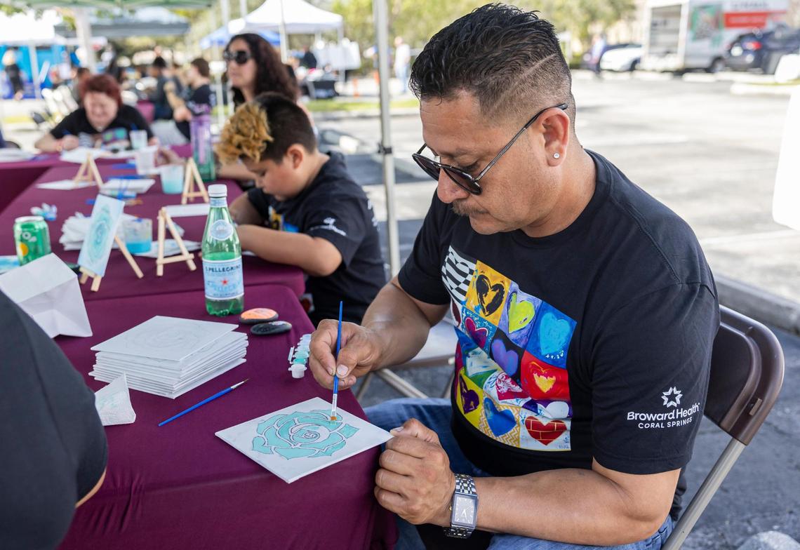 Martin Duque, the father of Martin Duque Jr., paints a rose during the ‘Forever in Our Hearts’ commemoration event outside of the Eagles’ Haven Wellness Center on Friday, Feb. 14, 2025, in Coral Springs, Fla. The event aims to honor the 17 lives lost during the Marjory Stoneman Douglas High School shooting in 2018 and their families.
