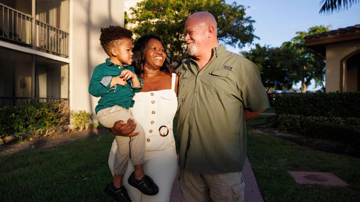 Ryan Hiott, right, poses with his son, Ryan Jr., left, and his wife, Erica, center, outside of their one-bedroom apartment on Wednesday, Oct. 23, 2024, in Miami. Hiott was laid off last year and, as he looks for jobs, is worried about losing benefits like free childcare and healthcare. Without that assistance, the family could not pay rent, which they can barely pay now.