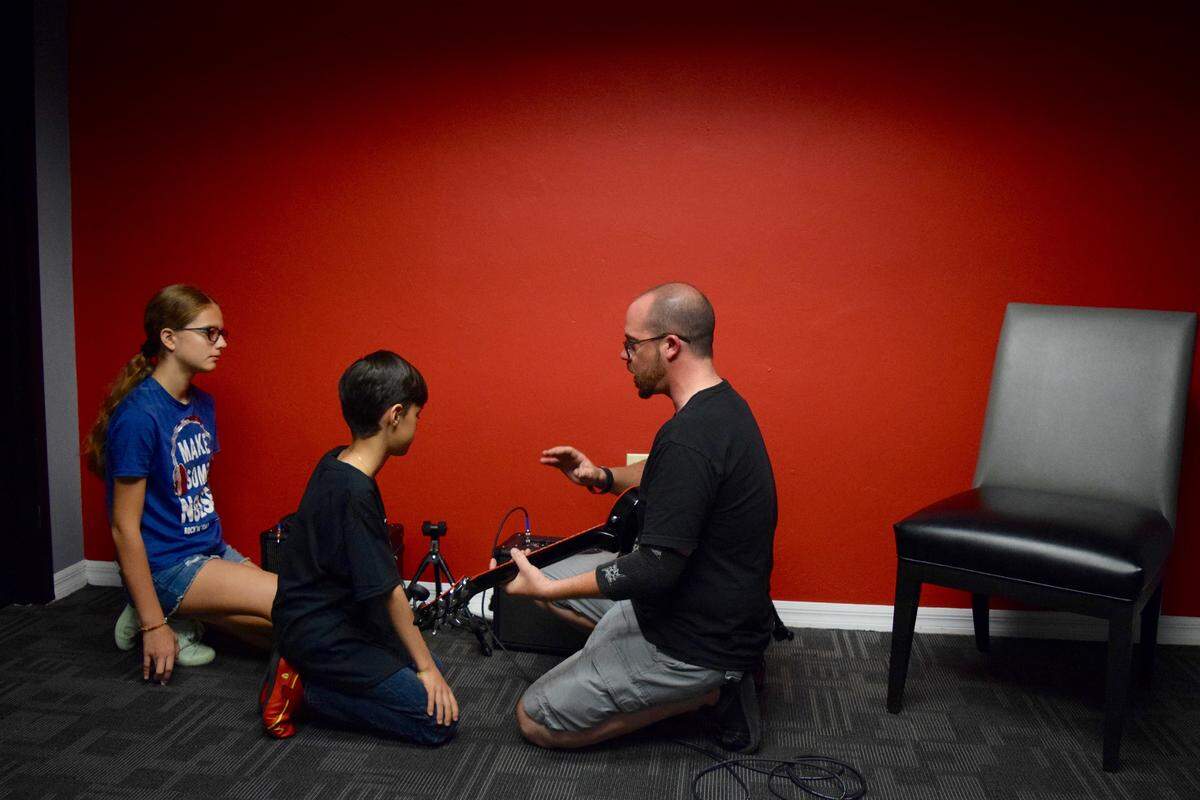 Guitar teacher Michael Stefanick mentors students Saturday at School of Rock in North Miami.