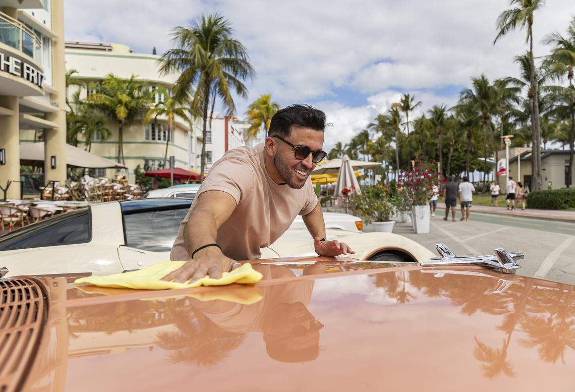 Enzo Murillo uses a yellow rag to clean the orange hood of a 1955 Chevrolet Bel Air on display at the Classic Car Show during Art Deco Weekend at Ocean Drive on Saturday, Jan. 10, 2026, in Miami Beach, Fla.
