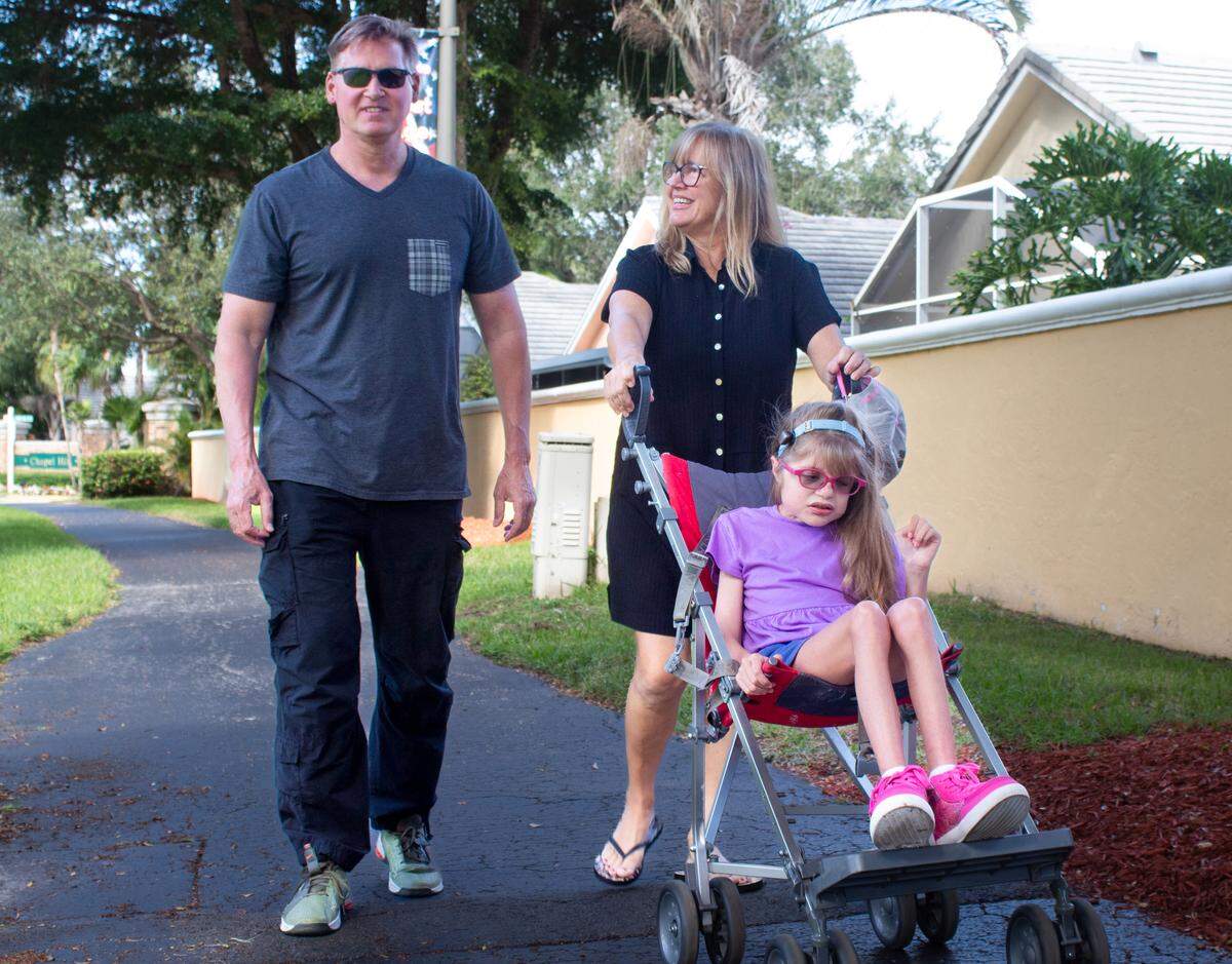 Every evening, Chris and Dina Lowe take their daughter Riley for a walk in her stroller. She wears specialized glasses to block the sun during a walk, one of her favorite activities.