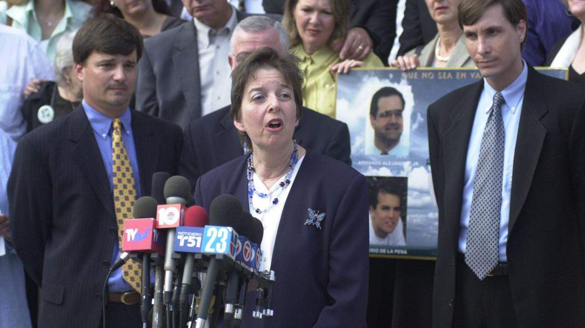 Caroline Heck Miller, the lead attorney with the U.S. Attorney’s Office, talks to the press in 2001 about the guilty verdicts of the five men in the spy and murder case in front of the U.S. Courthouse in Miami. Flanking Miller are Assistant U.S. Attorneys John Kastrenakes, left, and David Buckner, right. Family members and friends of the four killed in the shoot-down of Brothers to the Rescue planes stand on the steps behind them.