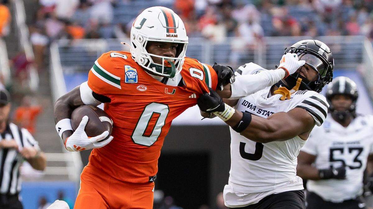 Miami Hurricanes wide receiver Joshisa Trader (0) stiff-arms Iowa State Cyclones defensive back Myles Purchase (5) as he runs with the ball to score a touchdown in the first half of their Pop-Tarts Bowl football game at the Camping World Stadium on Saturday, Dec. 28, 2024, in Orlando, Fla.