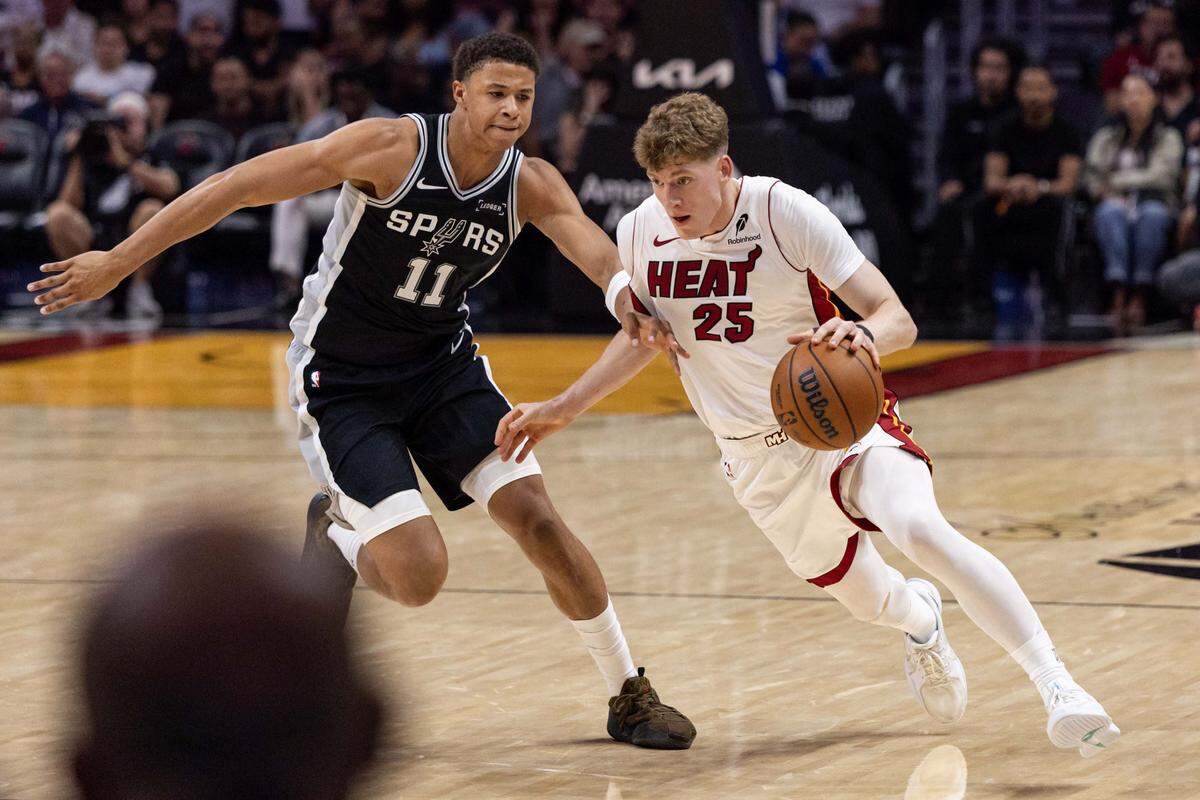 Miami Heat guard Kasparas Jakucionis (25) drives past San Antonio Spurs forward Carter Bryant (11) during the second half of an NBA preseason game at Kaseya Center on Wednesday, October  8, 2025, in Miami, Fla.