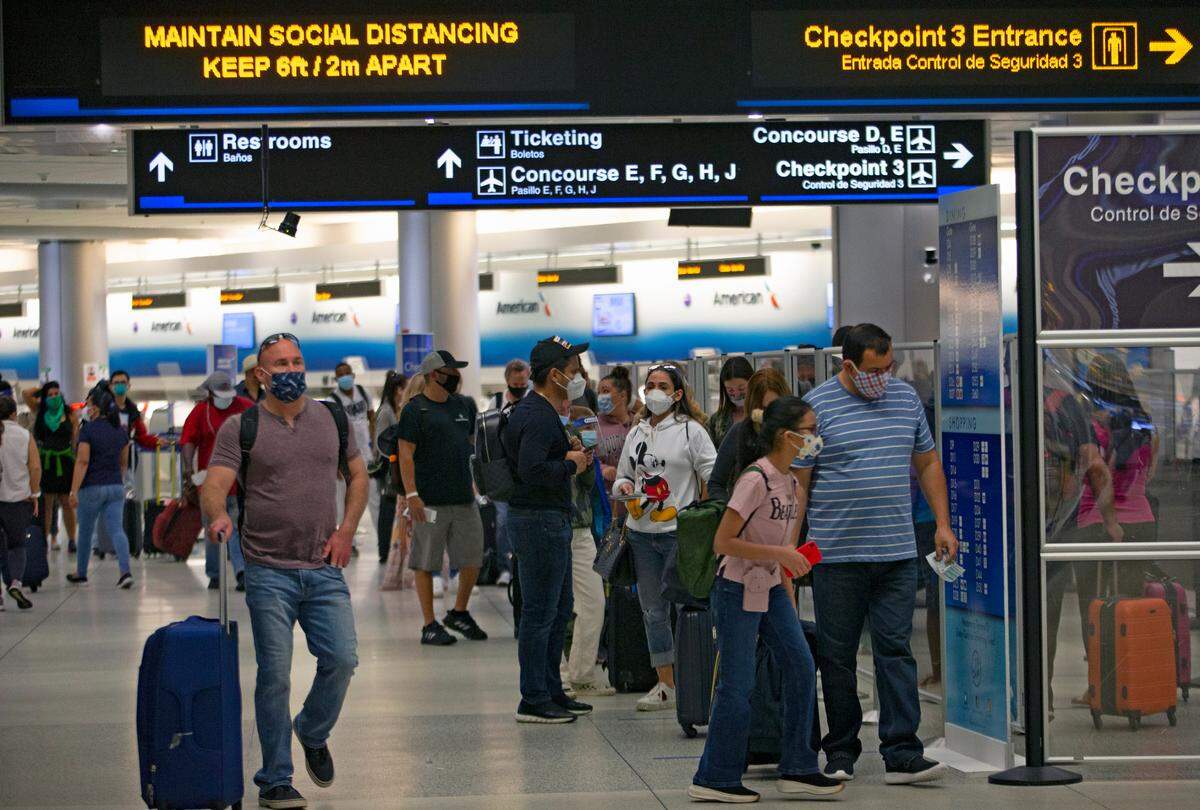 Viajeros con máscaras protectoras caminando por el pasillo D en el Aeropuerto Internacional de Miami el domingo 22 de noviembre de 2020 en Miami, Florida.