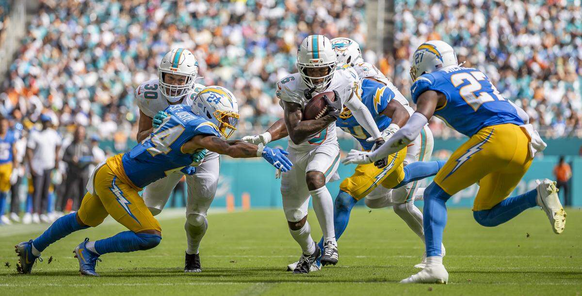 Miami Dolphins wide receiver Malik Washington (6) runs with the ball as Los Angeles Chargers cornerback Benjamin St-Juste (24) and safety R.J. Mickens (27) go for the tackle in the second half of their NFL game at Hard Rock Stadium on Sunday, Oct. 12, 2025, in Miami Gardens, Fla.