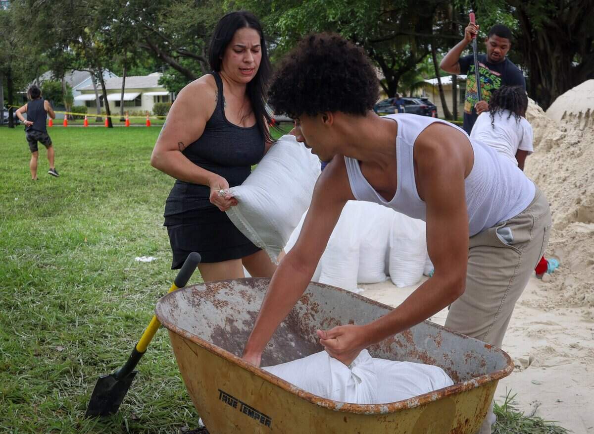 Mayra Revera, 43, left, and son, Johnmar Mulero, 16, load a wheelbarrow with sandbags as Hollywood residents join South Floridians in preparation for possible flooding due to Hurricane Milton in Broward and Miami-Dade counties at Jefferson Park in Hollywood, Florida, on Oct. 8, 2024.