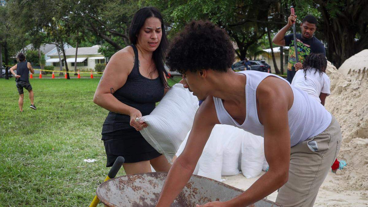Mayra Revera, 43, left, and son, Johnmar Mulero, 16, load a wheelbarrow with sandbags as Hollywood residents join South Floridians in preparation for possible flooding due to Hurricane Milton in Broward and Miami-Dade counties at Jefferson Park in Hollywood, Florida, on October 8, 2024.
