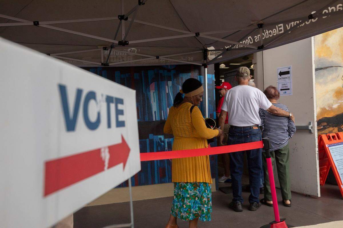 People stand on line to vote during the first day of in-person early voting for the 2024 election at the John F. Kennedy Library on Monday, Oct. 21, 2024 in Hialeah, Florida.