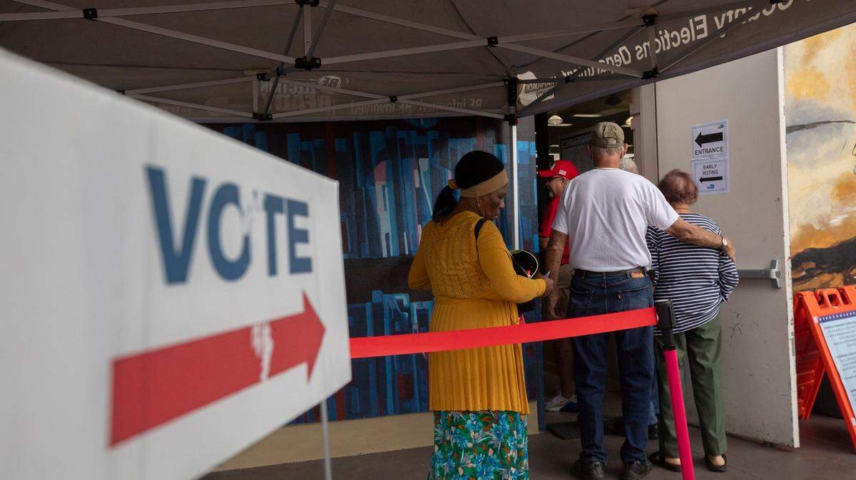 People stand on line to vote during the first day of in-person early voting for the 2024 election at the John F. Kennedy Library on Monday, Oct. 21, 2024, in Hialeah, Florida.