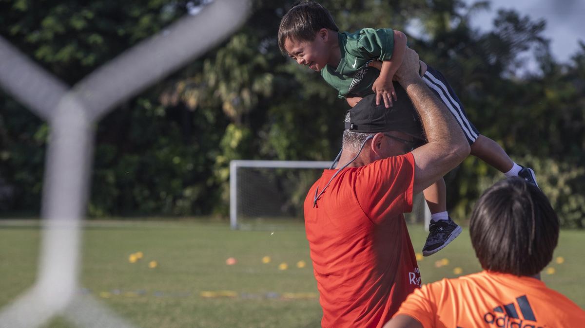 Coach Antonio Paz plays with Kyle Mueller, 4, at the soccer field in Pinecrest Gardens. The coach runs a soccer program for children with disabilities.