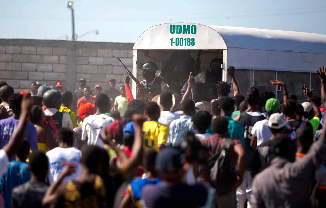 In this Dec. 10, 2018 photo, police guard an alleged gang member to keep the crowd from attacking him outside a police station in the La Saline slum of Port-au-Prince, Haiti. Residents believe the arrested man is one of the perpetrators of a Nov. 13 massacre in the La Saline slum.