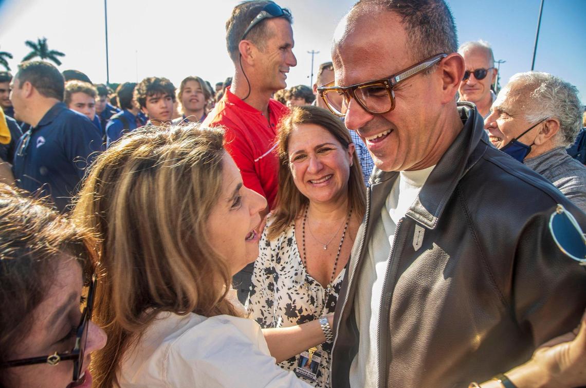 Entrepreneur and TV personality Marcus Lemonis shares hugs with teacher Amy Mallafre, center, and Nancy Pfaeffle, after his surprise announcement of his $10 million donation to build two centers and give $18,000 checks to all employees at his Miami alma mater on Thursday, Dec. 9, 2021.