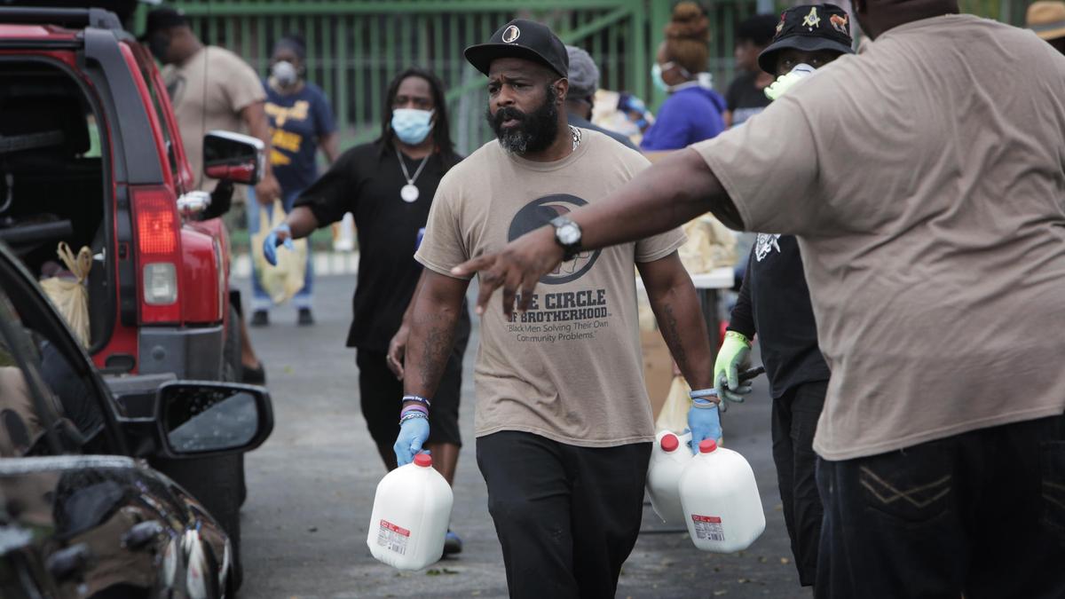 Volunteers hurry to fill the trunks of those who came to the food donation pick up spot in Overtown sponsored by Elliott’s Ark of the City, a non-profit, and Farm Share.