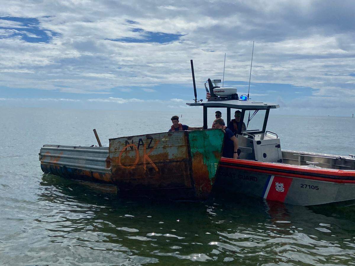 A U.S. Coast Guard crew moves a Cuban boat away from the channel on the ocean side of Tavernier Creek in the Florida Keys Friday, Oct. 14, 2022.