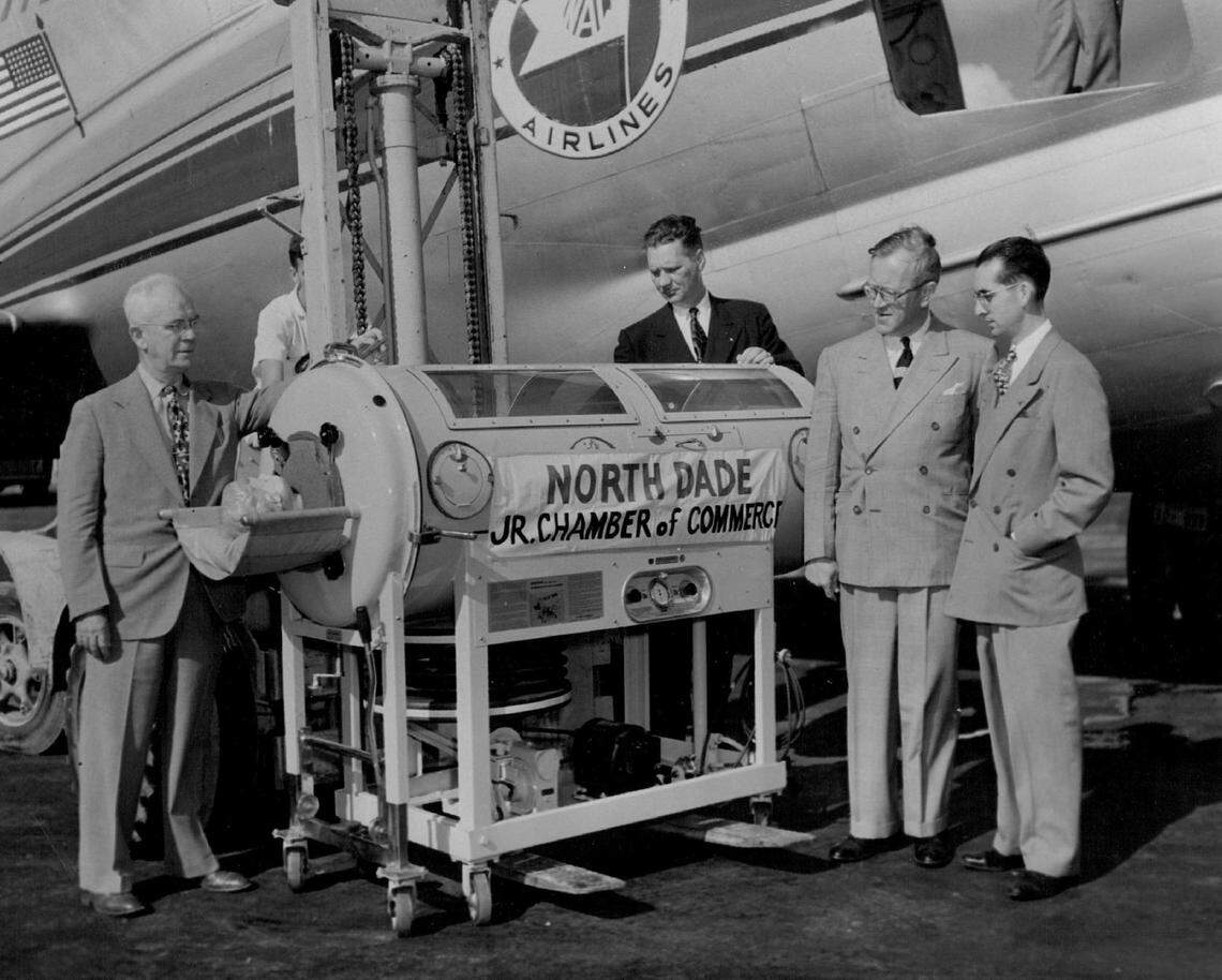 A donated iron lung arrives at the Miami airport, surrounded by city and civic officials.
