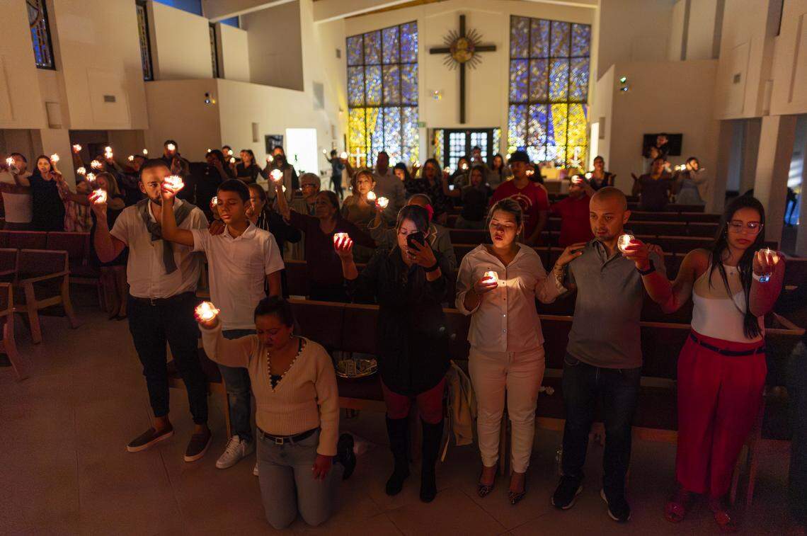 From right to left: Melissa Quiroz, Miguel Pereira, Laura, Yiralit Vanegas, Mayerly Susa, Juan Pablo Susa and Leandro Giraldo hold candles and pray during a vigil at Christ Lutheran Church.