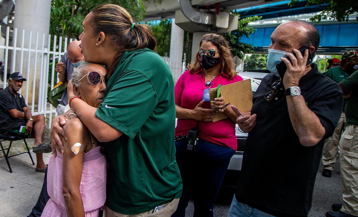 Ron L. Book, chair of the Miami-Dade Homeless Trust, talks on the phone as Outreach Specialist Johanna Carrasco comforts Belkis Perez, a homeless woman who is living under the I-95 underpass, after she received a shot of the (J&J/Janssen) COVID-19 vaccine.