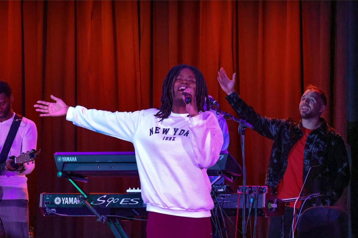 On stage Milly Guillaume, center, and Pastor Chancellor Dix, lift their hands while singing in praise during Collab.church’s Sunday service at North Dade Middle School in Miami Gardens.