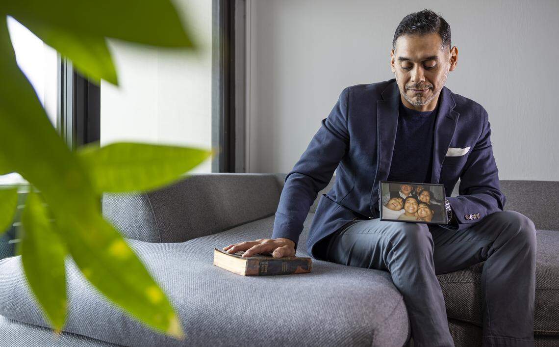 Mario Lopez holds a family photo at his home in Sunny Isles Beach, Florida. His brother, David Lopez, was struck and killed by a Brightline train while walking his dog in 2019.