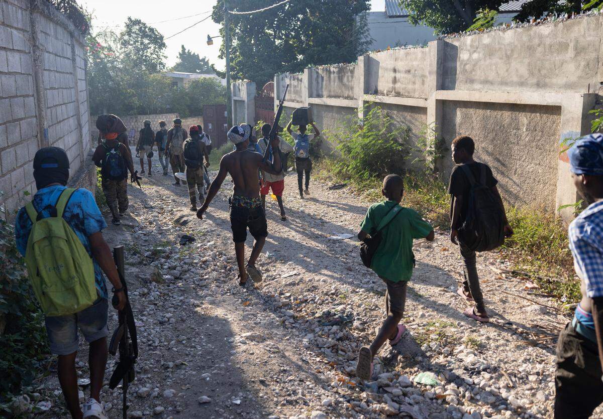 Gang members carry stolen goods after raiding a Port-au-Prince neighborhood on Dec. 6, 2024.