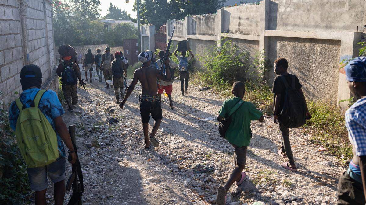 Gang members carry stolen goods after raiding a Port-au-Prince neighborhood on Friday, December 6, 2024. More than 1,000 schools have been closed in Haiti because of the gang crisis, and children often wear knapsacks to carry items they have found or looted.